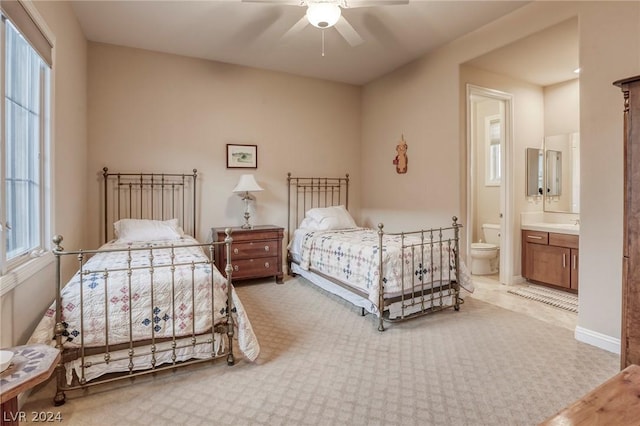 bedroom with multiple windows, ensuite bath, and ceiling fan