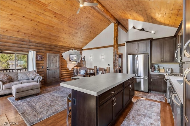 kitchen featuring a kitchen island, beamed ceiling, rustic walls, appliances with stainless steel finishes, and high vaulted ceiling