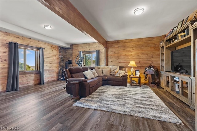 living room featuring beam ceiling, plenty of natural light, dark hardwood / wood-style floors, and wood walls