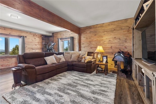 living room featuring dark wood-type flooring, wooden walls, and beamed ceiling