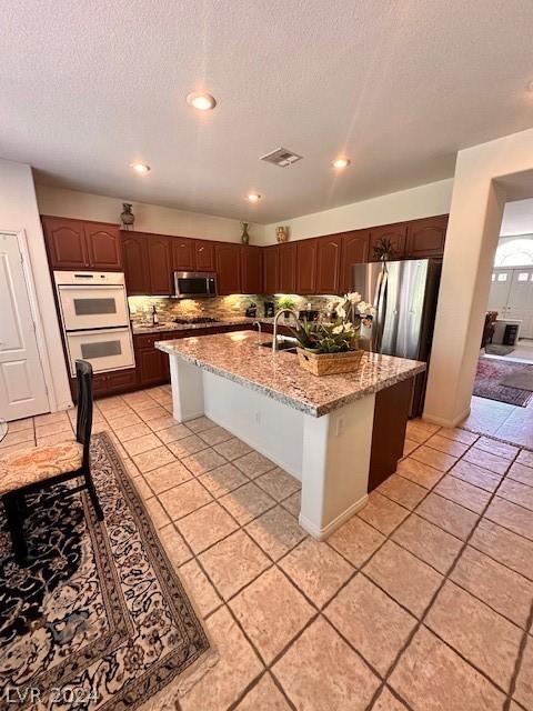 kitchen with stainless steel appliances, sink, an island with sink, and a breakfast bar area