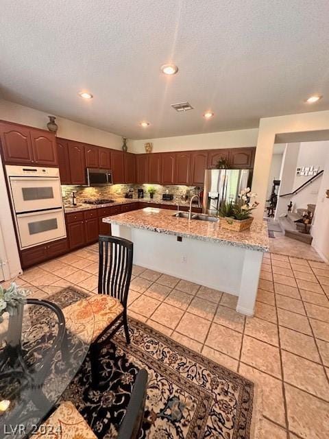 kitchen featuring light tile patterned flooring, tasteful backsplash, sink, a kitchen breakfast bar, and stainless steel appliances