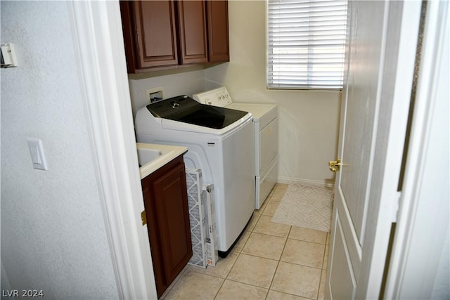 laundry room featuring cabinets, separate washer and dryer, and light tile patterned floors