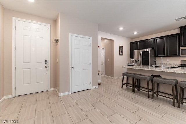 kitchen featuring sink, light stone countertops, stainless steel appliances, and a breakfast bar area