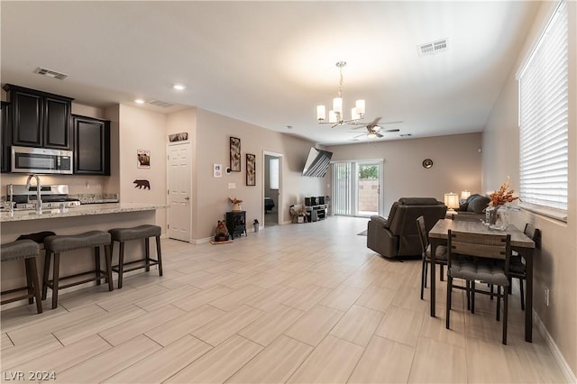 living room with ceiling fan with notable chandelier and sink