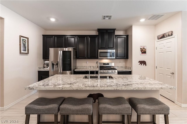 kitchen with a breakfast bar, a center island with sink, and stainless steel appliances