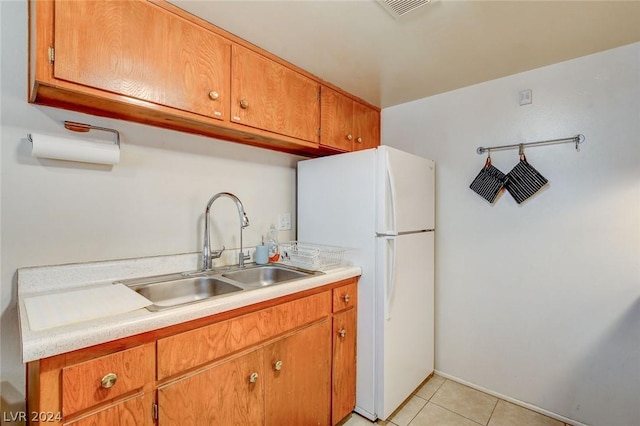 kitchen featuring light tile patterned flooring, white fridge, and sink