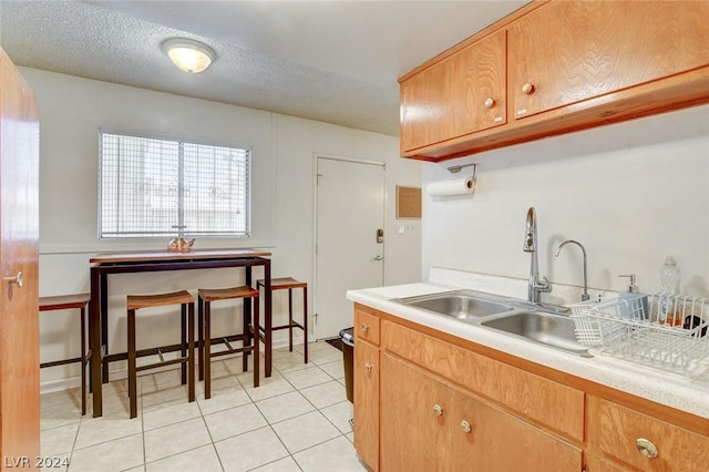 kitchen with sink, a textured ceiling, and light tile patterned floors