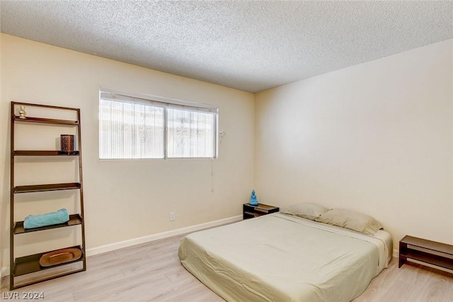 bedroom featuring a textured ceiling and light hardwood / wood-style floors