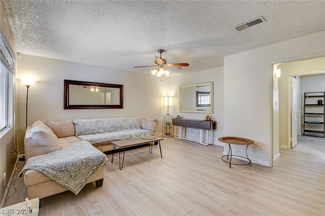 living room with ceiling fan, light hardwood / wood-style floors, and a textured ceiling