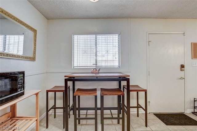 dining room with a textured ceiling and light tile patterned floors