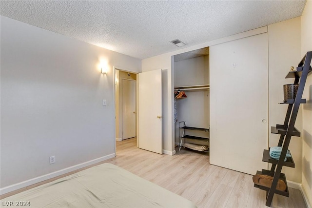 bedroom with light hardwood / wood-style flooring, a closet, and a textured ceiling