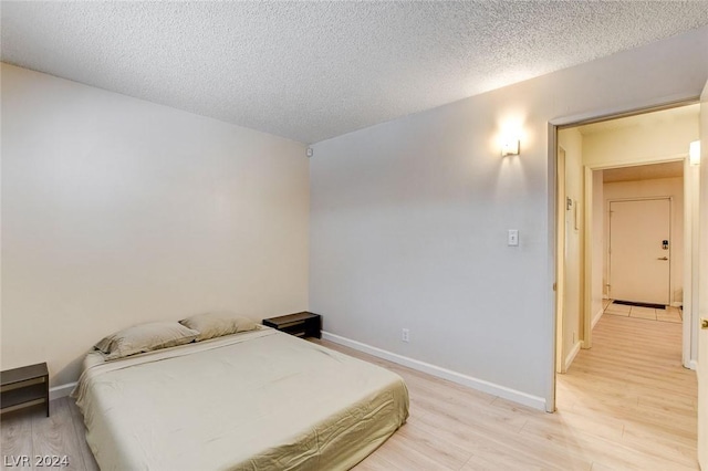 bedroom with a textured ceiling and light hardwood / wood-style flooring