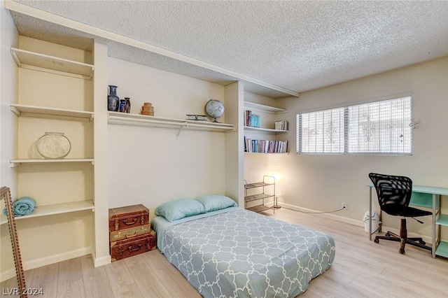 bedroom with hardwood / wood-style floors and a textured ceiling