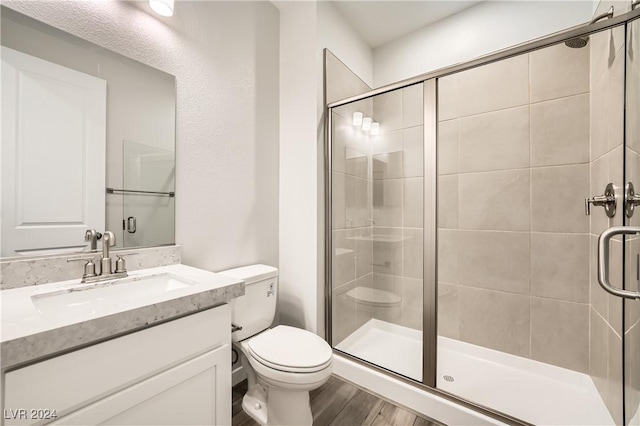 bathroom with hardwood / wood-style floors, vanity, and a shower with shower door