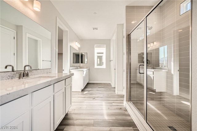 bathroom with hardwood / wood-style flooring, a shower with door, and vanity