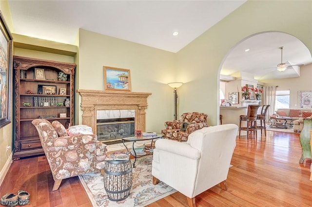 living room featuring ceiling fan, lofted ceiling, and light hardwood / wood-style flooring