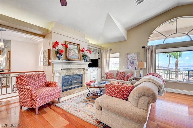 living room featuring light wood-type flooring, lofted ceiling, and a tiled fireplace