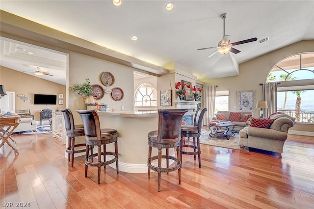 kitchen featuring a kitchen bar, hardwood / wood-style flooring, vaulted ceiling, and ceiling fan