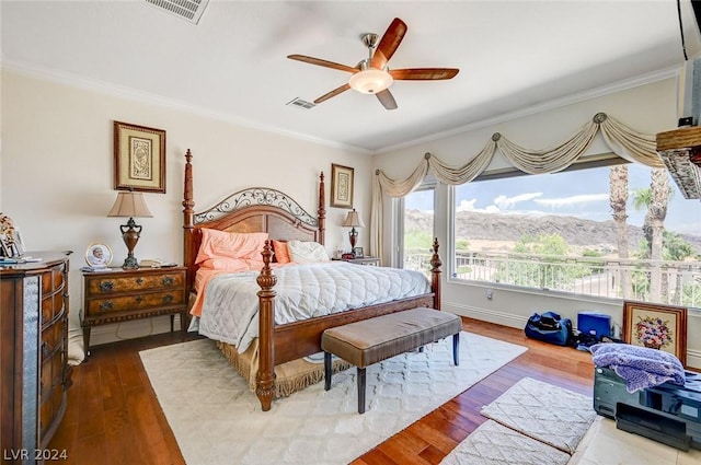 bedroom with hardwood / wood-style flooring, ceiling fan, a mountain view, and crown molding