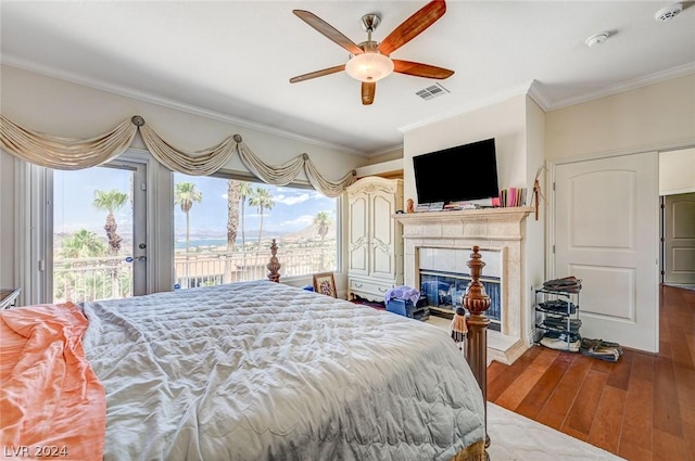 bedroom featuring a tile fireplace, ceiling fan, hardwood / wood-style floors, access to outside, and ornamental molding