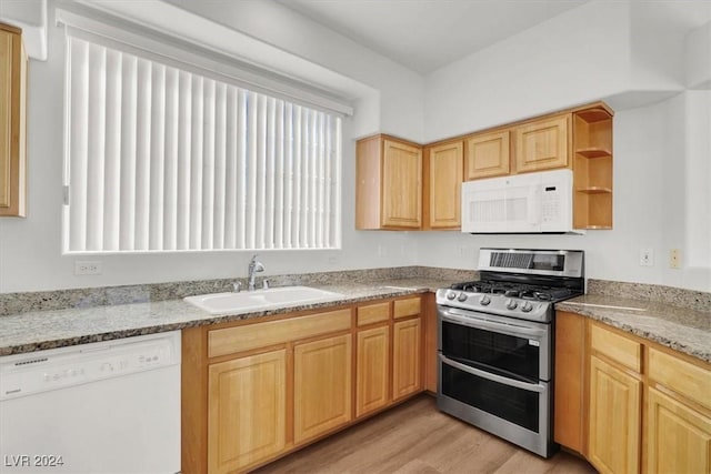 kitchen with sink, white appliances, light wood-type flooring, light stone countertops, and light brown cabinets