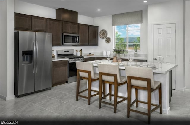 kitchen featuring dark brown cabinets, stainless steel appliances, a kitchen breakfast bar, and a center island with sink