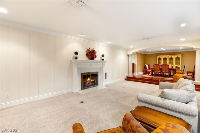 carpeted living room featuring crown molding and decorative columns