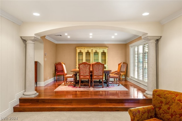 dining room with crown molding, wood-type flooring, and decorative columns