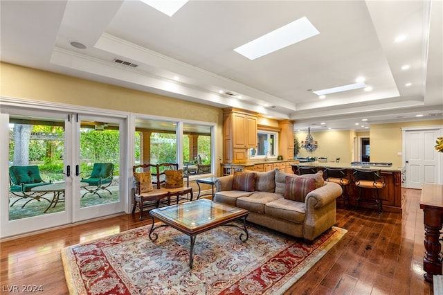 living room featuring a skylight, a healthy amount of sunlight, and a raised ceiling