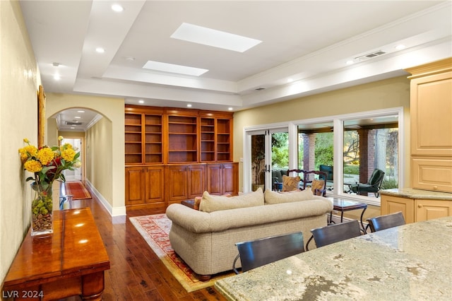 living room with a skylight, crown molding, dark hardwood / wood-style floors, and a tray ceiling