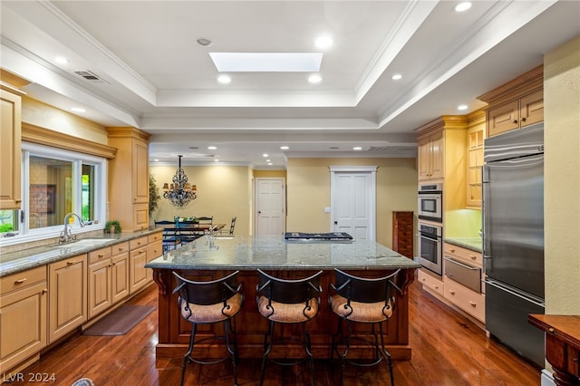 kitchen with appliances with stainless steel finishes, sink, light brown cabinets, and a spacious island