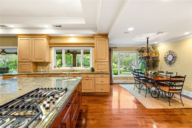 kitchen featuring dark hardwood / wood-style floors, stainless steel gas cooktop, light brown cabinetry, light stone countertops, and crown molding