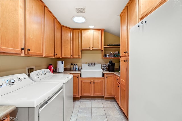 laundry area with light tile patterned flooring, cabinets, washer and dryer, and sink