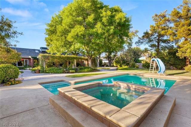 view of swimming pool with an in ground hot tub and a water slide