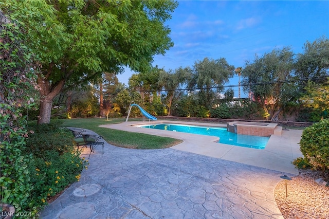 view of swimming pool featuring a yard, a water slide, a patio, and an in ground hot tub