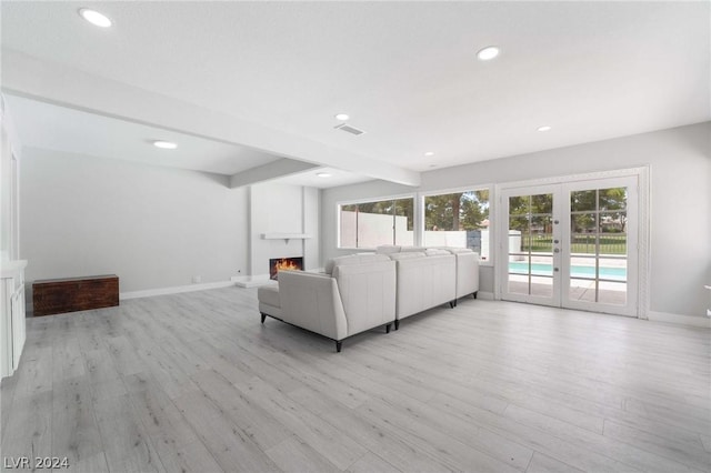 unfurnished living room featuring french doors, beam ceiling, and light wood-type flooring