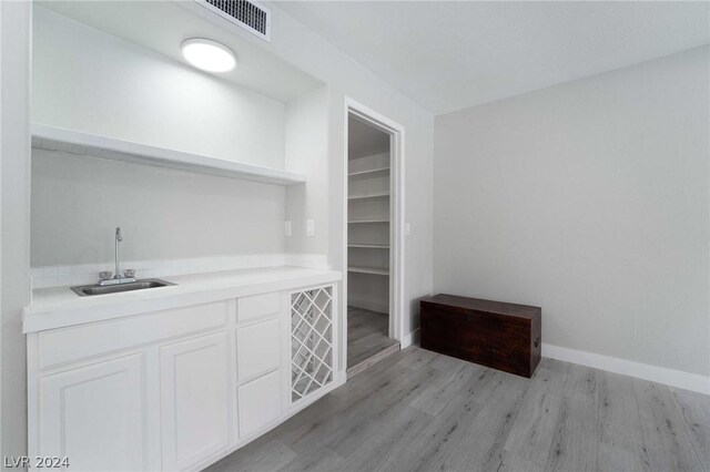 bar featuring sink, white cabinets, and light wood-type flooring