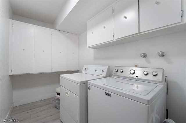 laundry room featuring separate washer and dryer, light hardwood / wood-style floors, and cabinets