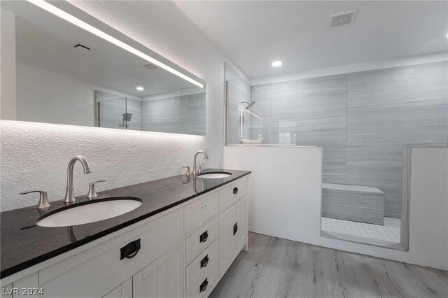 bathroom with vanity, hardwood / wood-style floors, and a tile shower