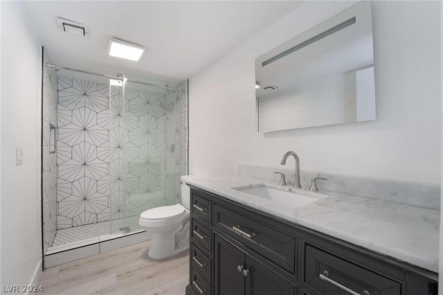 bathroom featuring wood-type flooring, toilet, a shower with shower door, and vanity