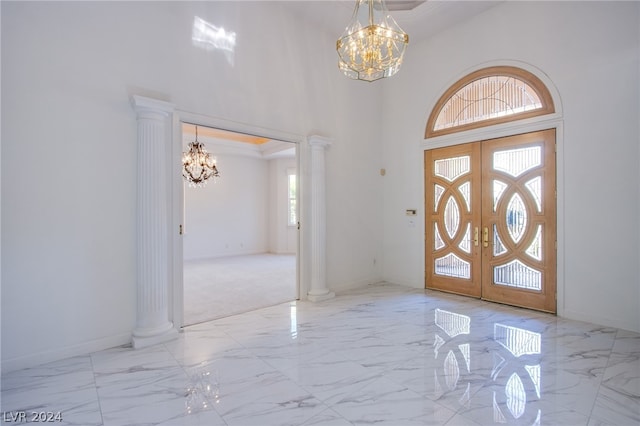 tiled entryway with a notable chandelier, decorative columns, french doors, and a towering ceiling