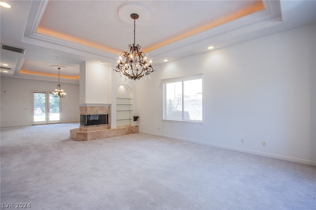 unfurnished living room with an inviting chandelier, a fireplace, carpet floors, and a raised ceiling