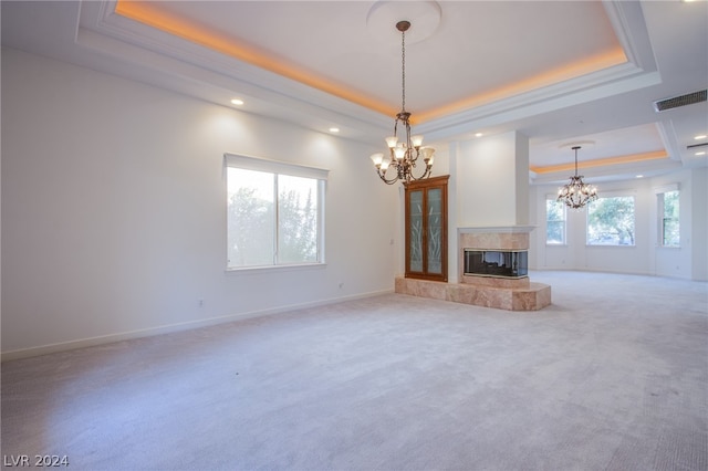 unfurnished living room with a raised ceiling, a notable chandelier, and a wealth of natural light