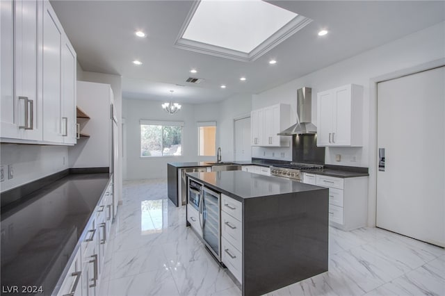 kitchen featuring a skylight, white cabinetry, light tile patterned floors, a kitchen island, and wall chimney exhaust hood