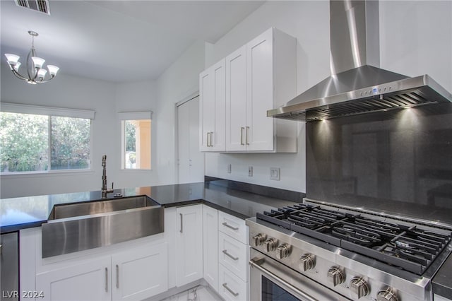 kitchen featuring a notable chandelier, wall chimney range hood, white cabinets, sink, and high end stainless steel range