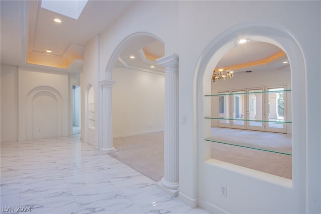 hall with an inviting chandelier, tile patterned flooring, and a raised ceiling