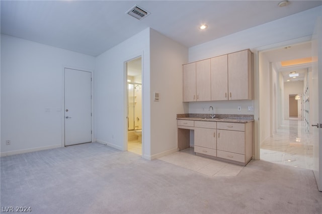 kitchen with light carpet, light stone counters, sink, and light brown cabinetry