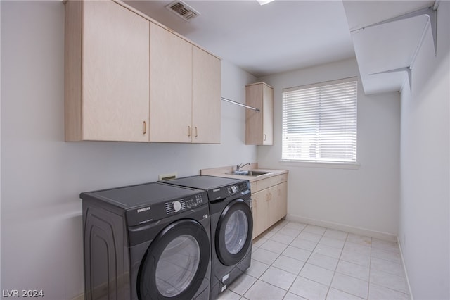 washroom with light tile patterned flooring, sink, cabinets, and independent washer and dryer