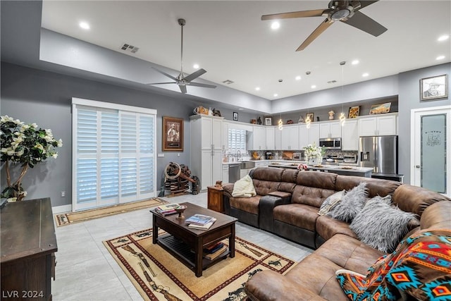 living room featuring light tile patterned flooring, ceiling fan, and sink